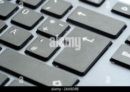 Enter key on a simple generic grey office desktop PC keyboard, object detail, macro, extreme closeup, nobody, no people. Bright gray computer keyboard Stock Photo