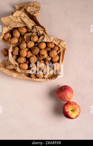 Two apples, and some walnuts, on a delicate pink background. Stock Photo