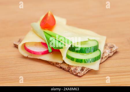 Whole Grain Crispbread with Cheese, Fresh Cucumber, Radish, Tomato and Green Onions on Cutting Board. Quick and Healthy Sandwiches. Crispbread with Tasty Filling. Healthy Dietary Snack Stock Photo