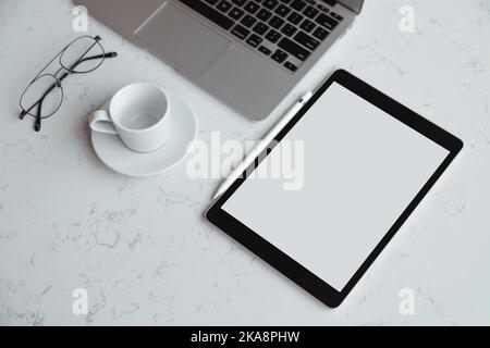 Opened laptop with digital tablet with white blank screen. On marble table, workplace Stock Photo