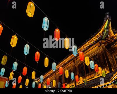 A view of colorful garland-like lights hanging from wires in the city at night Stock Photo