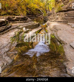 Small Creek Flowing Under Eroded Cliffs With Fall Color, Devils Bathtub Trail, Spearfish Canyon, South Dakota, USA Stock Photo