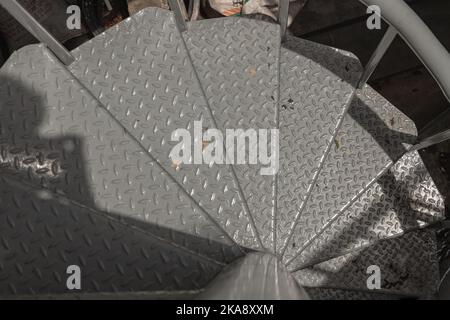 Top view of metal steps of outside spiral staircase with sunlight and shadow on surface. Steel spiral stairs ladder, Spiral staircase pattern, Selecti Stock Photo