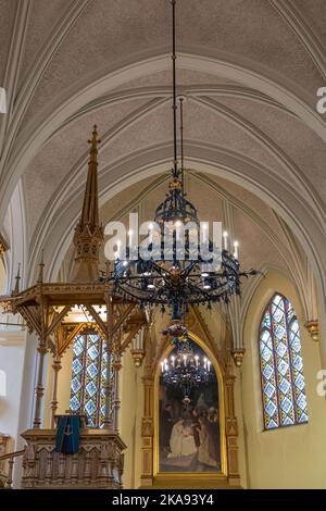 Finland, Kotka - July 18, 2022: Kotka-Kymin Parish Church or Seurakuntayhtymä. Artful and elaborate hanging light fixture with pulpit and painting in Stock Photo