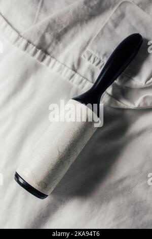 white sticky lint roller with black hairs on white sheets Stock Photo