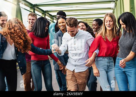 Multiethnic friends having fun walking together carefree - interracial community of young people standing together and walking under a bridge - divers Stock Photo