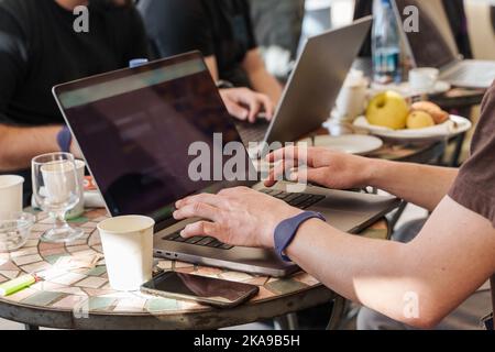 Smart men in casual style working on their laptop computers in team at the coffee shop cafe at brunch time - technology and remote working lifestyle c Stock Photo