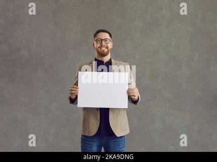 Smiling businessman holding blank paper poster looking at camera Stock Photo