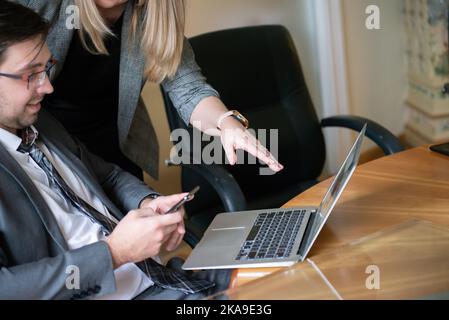 Roundtable meeting of business partners. Business people talking and using laptops and phone. Stock Photo