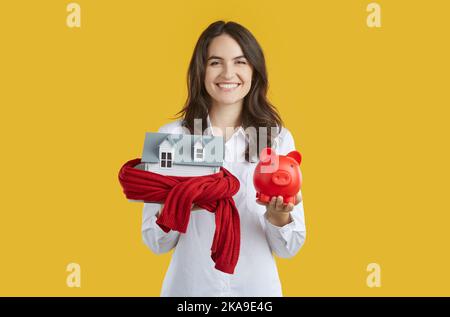 Happy real estate agent holding piggy bank and model of house for Christmas sale Stock Photo