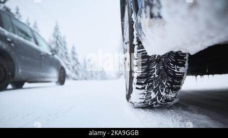 Close-up view of tire of car on snow covered and icy road. Themes safety and driving in winter. Stock Photo