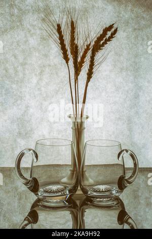 Two empty beer glasses on the background of a vase with barley ears Stock Photo