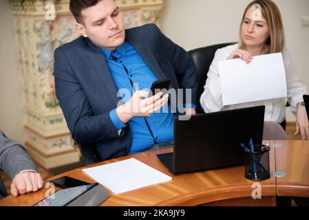 Roundtable meeting of business partners. Business people talking and using laptops and phone. Stock Photo