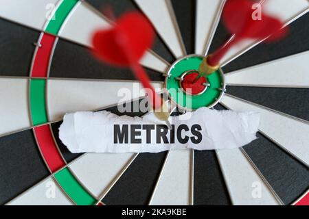 Target. The picture shows a target, darts and a torn piece of paper with the inscription - METRICS Stock Photo