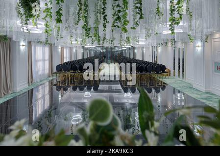 Hotel conference hall with empty chairs, green design with green plants and flowers. Stock Photo