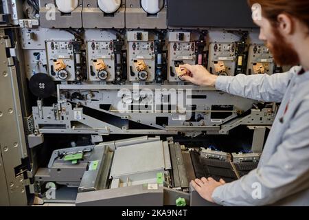 Close up of worker operating industrial printing machines in workshop, copy space Stock Photo
