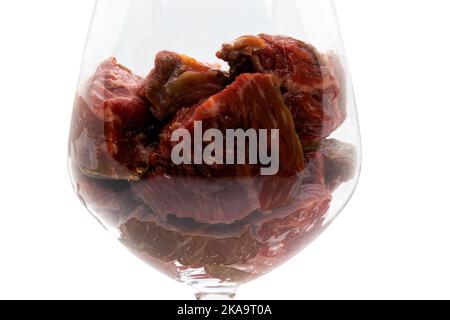 Close up of a red wine glass filled with pieces of red meat. Isolated on white background with clipping path. Stock Photo