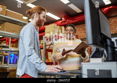 Portrait of two young people working in print shop and using computer, copy space Stock Photo