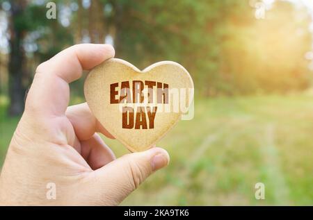 Ecological concept. In the hands of a man is a tablet in the form of a heart on which it is written - earth day Stock Photo