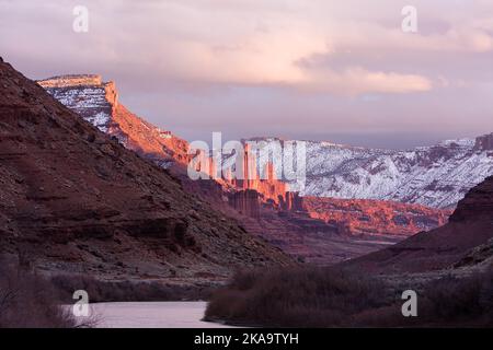 Fisher Towers over the Colorado River at sunset in winter with the La Sal Mountains behind.  Near Moab, Utah. Stock Photo