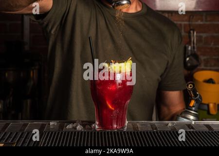 Barman in the bar preparing a alcohol cocktail in a glass. Summer party background. Stock Photo