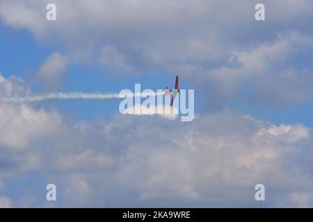 Plane flying within dark clouds with smoke on tail Stock Photo