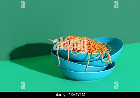 Pasta Pomodoro in dish stacked on empty bowls on a green-colored table. Spaghetti with tomato sauce in bright light against a vibrant background. Stock Photo