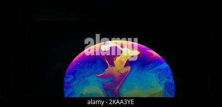 Half a soap bubble. Close-up. Black background. Bright colors. Side view. Imitation of an unknown planet. Science fiction Stock Photo