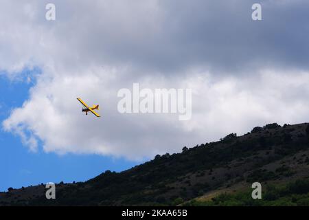 Small single engine propeller plane flying within clouds in a sunny day Stock Photo