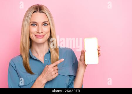 Portrait of nice charming pretty woman with blond hair indicating at touchscreen demonstrating screen isolated on pink color background Stock Photo