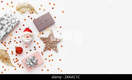 Christmas and New Year background with decorations. Santa Claus, golden feathers, silver presents and stars confetti. Copy space. Stock Photo