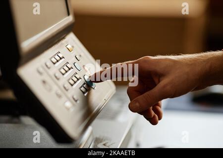 Side view close up of male hand pressing start button on printing machine, copy space Stock Photo