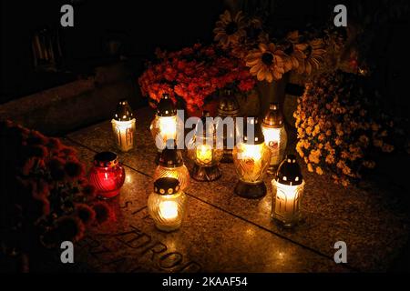 Warsaw, Poland. 01st Nov, 2022. Candles and flowers are seen at the tomb on All Saints' Day at the Pow?zki Cemetery. All Saints' Day/All Souls' Day (or Dzie? Zaduszny in Polish) is a public holiday and an opportunity to remember the dead. On this day people take flowers and candles to cemeteries. In the darkness all the cemetery is full of lights. Pow?zki Cemetery (or Old Pow?zki) is a historic necropolis in Warsaw. It is the most famous cemetery in the city and one of the oldest. Credit: SOPA Images Limited/Alamy Live News Stock Photo