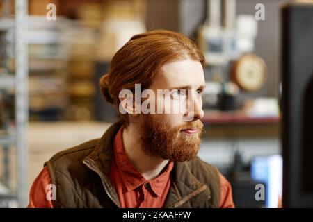 Close up portrait of bearded young worker looking focused in factory setting Stock Photo