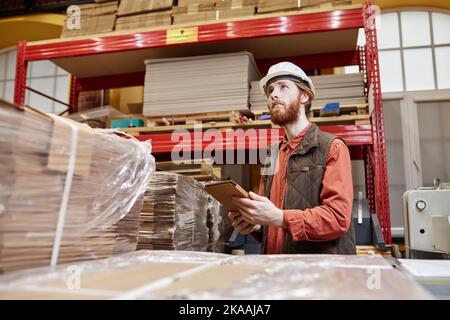 Waist up portrait of male worker wearing hardhat in factory workshop and using digital tablet, copy space Stock Photo