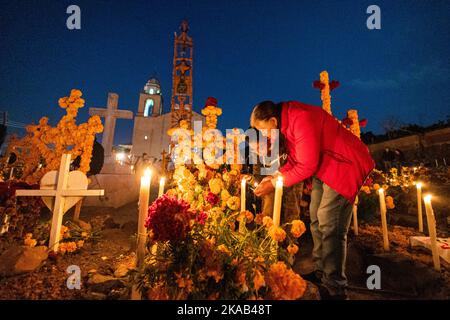 Morelia, Mexico, 1 Nov 2022, Mother and son light candles during the Day of the Dead celebration in the cemetery of Arocutin, Michoacan, Mexico. The indigenous Purepecha of this village prepare this annual ritual of remembrance by constructing altars with marigolds, candles and the favorite food or drink of the deceased.  The vigil takes place the night of November 1st and has become a major tourist attraction in the central Mexican state of Michoacan.  Brian Overcast/Alamy Live News Stock Photo