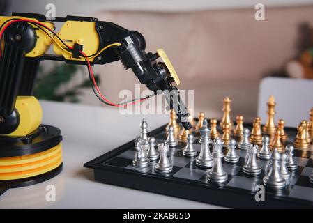 Closeup yellow robot arm playing move chess on chessboard Stock Photo