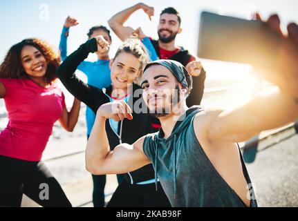Ending the session with a powerful selfie. a fitness group taking a selfie while out for a run on the promenade. Stock Photo