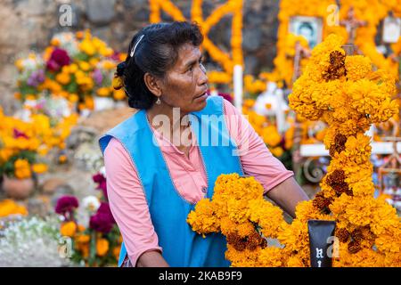 Morelia, Mexico, 1 Nov 2022, A Purepecha woman with marigold flowers during the Day of the Dead celebration in the cemetery of Arocutin, Michoacan, Mexico. The indigenous Purepecha of this village prepare this annual ritual of remembrance by constructing altars with marigolds, candles and the favorite food or drink of the deceased.  The vigil takes place the night of November 1st and has become a major tourist attraction in the central Mexican state of Michoacan.  Brian Overcast/Alamy Live News Stock Photo