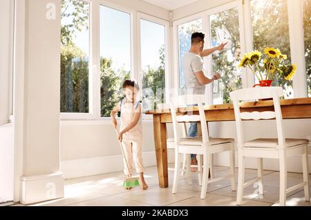 Teach kids to take some responsibility around the house. a father and his little daughter doing chores together at home. Stock Photo