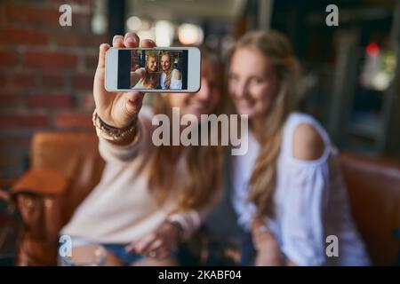 Theyre always taking selfies. two attractive young girlfriends taking selfies while sitting in a cafe. Stock Photo
