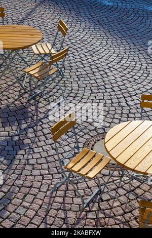 Outdoor German cafe seating with round tables and wooden  chairs Stock Photo