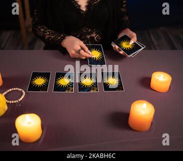 Fortune teller hands and tarot cards on wooden table. Divination Stock Photo