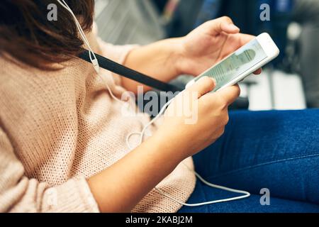 Passing the time. High angle shot of an unrecognizable young woman using her smartphone while sitting on a bus. Stock Photo