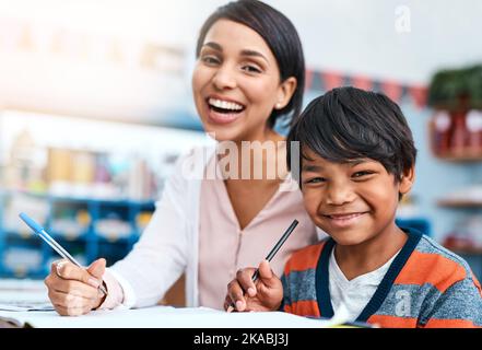 Miss always helps me when Im struggling. Portrait of a cheerful young female teacher helping a student inside of the class at school. Stock Photo