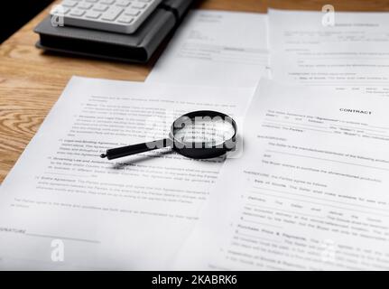 Paper contract and business documents on office desk with magnifying glass. Stock Photo