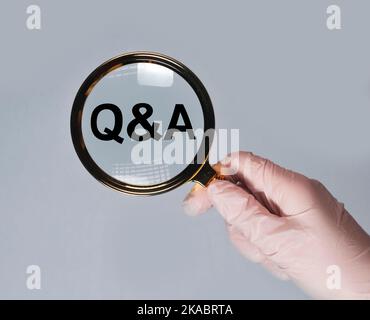 Health Q and A concept. Questions and answers about medicare. Medical QA, QnA through ,agnifying glass in doctor hand. Stock Photo