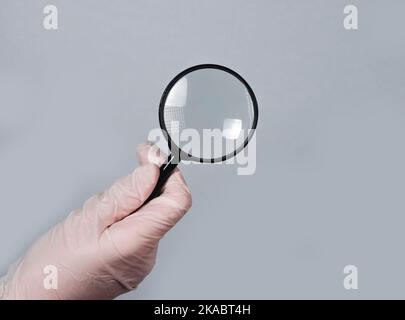 Doctors hand hold magnifying glass, searching treatment and examining diseases with optical lens concept. Stock Photo