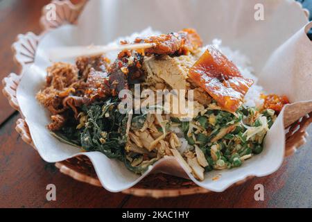 A plate of Balinese typical food called nasi babi guling or pork roll with rice in English, specialty consisting of pork meat, pork belly, pork skin, Stock Photo