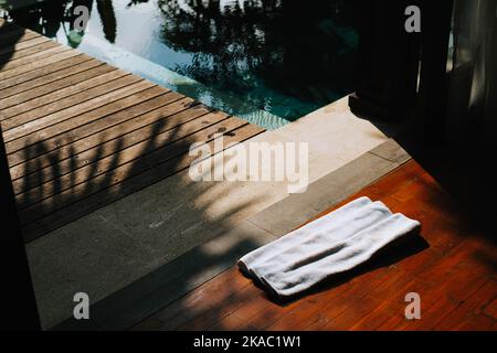 A white towel to dry in wooden floor in front of the room near the pool Stock Photo